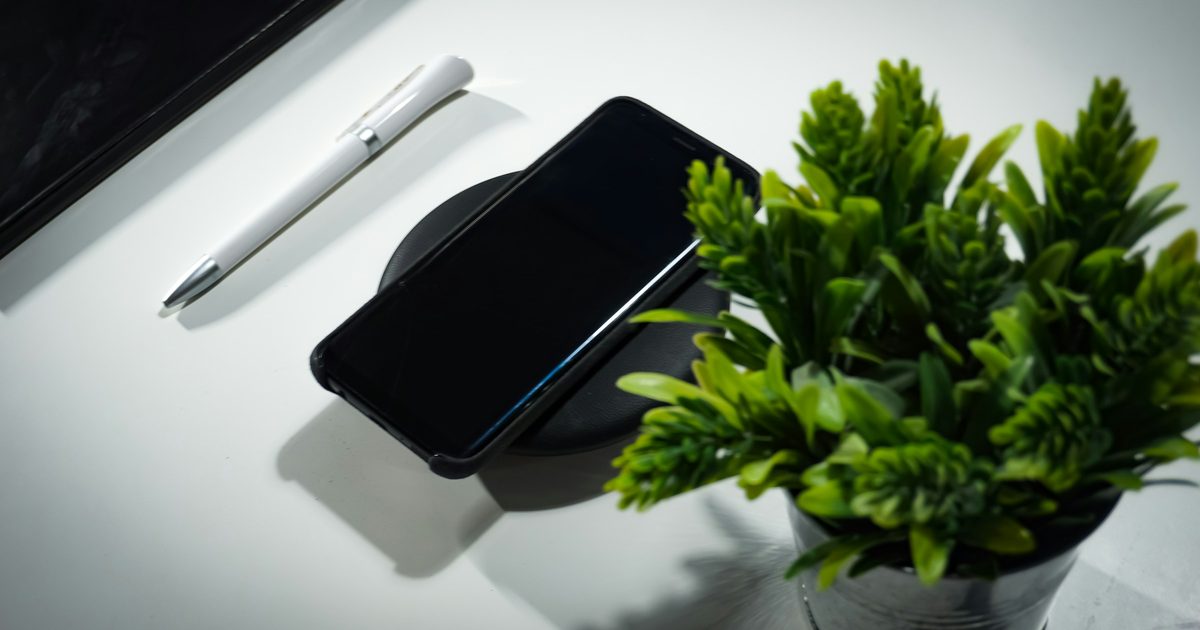 ワイヤレス充電器に置いた黒いスマホと観葉植物