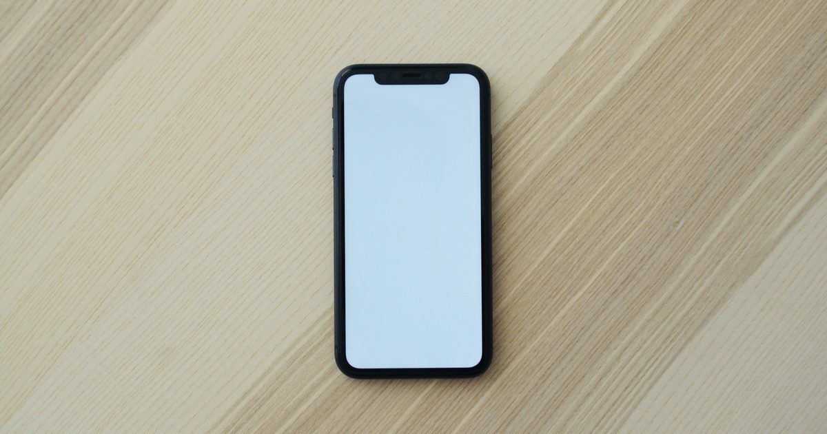明るい木の机に置いた黒いスマホ