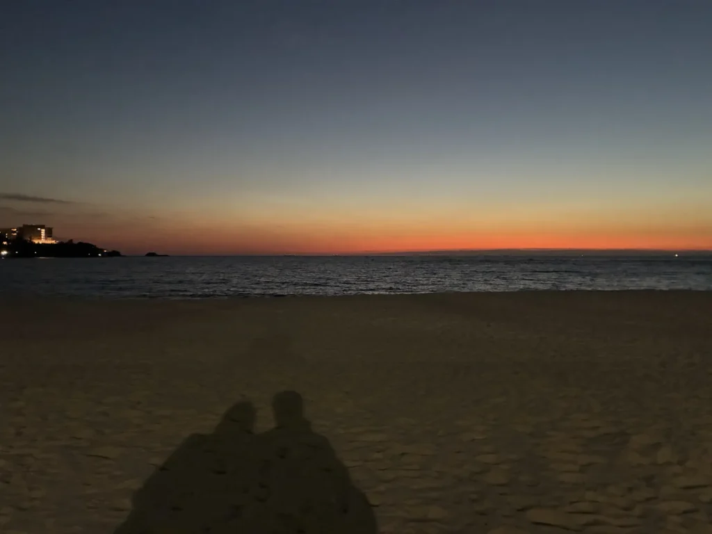 夕焼けの白浜の砂浜に並ぶ2人の影